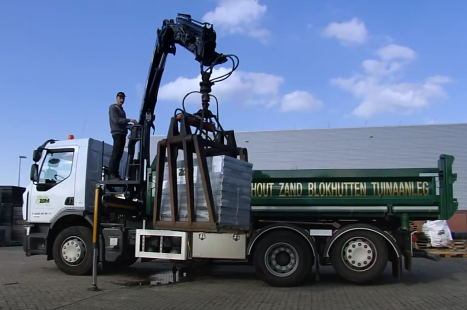 Een werknemer van ZAM Sierbestrating, Tuinhout & Hoveniers laadt een bestelling in de vrachtwagen